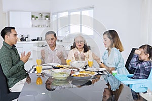 Multi generation family praying before having meals