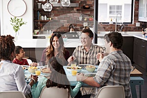 Multi Generation Family Praying Before Meal Around Table At Home