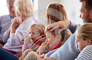 Multi-Generation Family Relaxing At Home Sitting On Sofa Watching Television Together