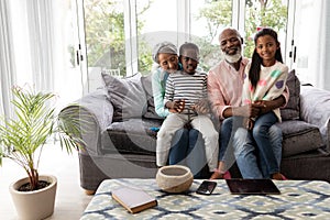 Multi-generation family relaxing together on a sofa in living room at home