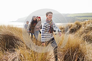 Multi Generation Family In Sand Dunes On Winter Beach