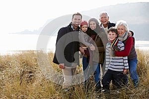 Multi Generation Family In Sand Dunes On Winter Beach