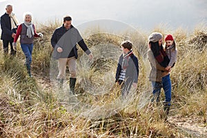 Multi Generation Family In Sand Dunes On Winter Beach