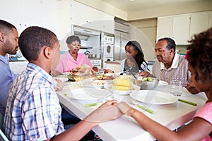 Multi-Generation Family Saying Prayer Before Eating Meal photo