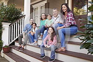 Multi Generation Family Sit On Steps Leading Up To House Porch