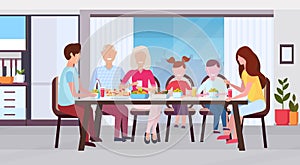 Multi generation family sitting around table eating meal together happy grandparents parents and children modern kitchen