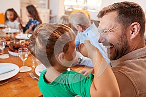 Multi-Generation Family Sitting Around Table Enjoying Meal At Home Together