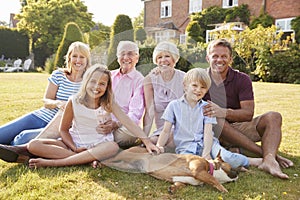 Multi generation family sitting on grass in the garden