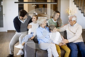 Multi generation family sitting together on the sofa at home and watching TV