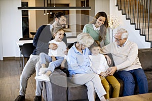 Multi generation family sitting together on the sofa at home and watching TV