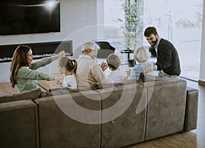 Multi generation family sitting together on the sofa at home and watching TV