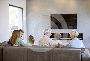 Multi generation family sitting together on the sofa at home and watching TV