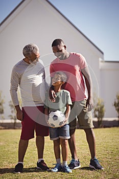 Multi-generation family standing in garden with football