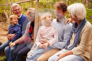 Multi-generation family talking on a bridge in a forest