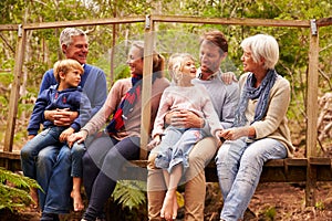 Multi-generation family talking on a bridge in a forest