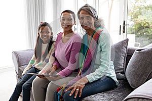 Multi-generation family using digital tablet on a sofa in living room at home