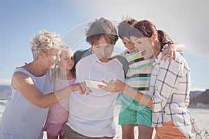 Multi-generation family using mobile phone at beach
