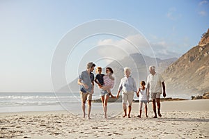 Multi Generation Family On Vacation Walking Along Beach Together