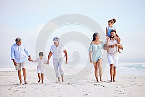 Multi generation family on vacation walking along the beach together. Mixed race family with two children, two parents