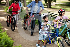 Multi-generation family walking with bicycle in park