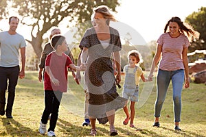 Multi-Generation Family Walking In Countryside Against Flaring Sun