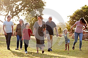 Multi-Generation Family Walking In Countryside Against Flaring Sun