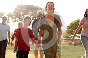 Multi-Generation Family Walking In Countryside Against Flaring Sun