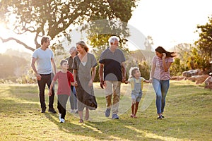 Multi-Generation Family Walking In Countryside Against Flaring Sun