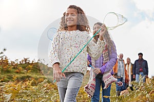 Multi-Generation Family Walking Through Countryside Carrying Fishing Nets On Winter Beach Vacation