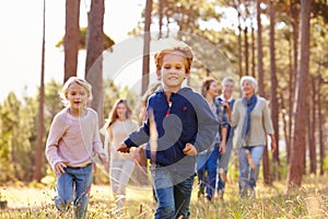 Multi-generation family walking in countryside, kids running