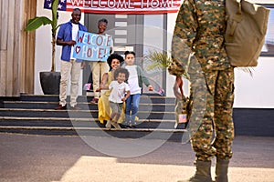 Multi-Generation Family Welcoming Army Father Home On Leave With Banner