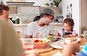 Multi-Generation Mixed Race Family Eating Meal Around Table At Home Together