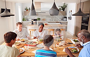 Multi-Generation Mixed Race Family Eating Meal Around Table At Home Together