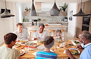 Multi-Generation Mixed Race Family Eating Meal Around Table At Home Together photo