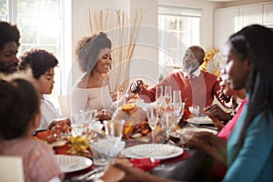 Multi generation mixed race family holding hands and saying grace before eating at their Thanksgiving dinner table, selective focu