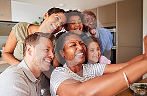 Multi-Generation Mixed Race Family Posing For Selfie As They Eat Meal Around Table At Home Together