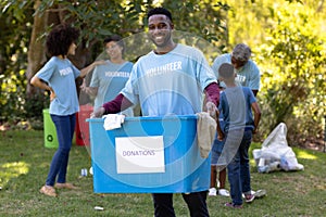 Multi-generation people collecting garbage with a man holding a box written Donations