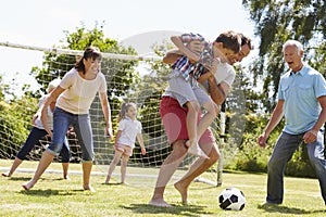 Multi Generation Playing Football In Garden Together