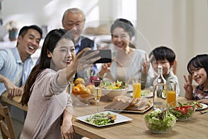 Multi generational asian family taking a selfie at dining table