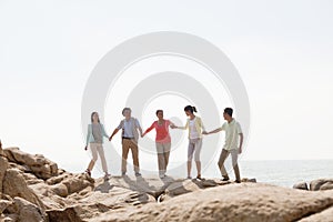 Multi-generational family holding hands on rocks by the sea