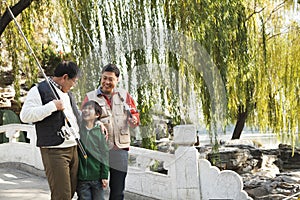 Multi-generational men walking with fishing gear at lake