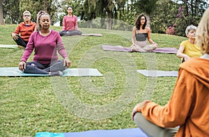 Multi generational people doing yoga class at city park - Focus on left senior woman face