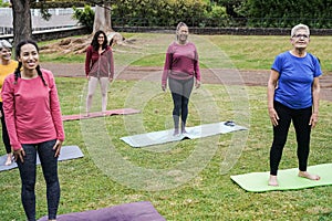 Multi generational people doing yoga class at city park - Main focus on african woman face