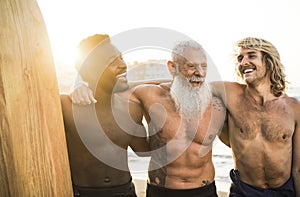 Multi generational surfer friends having fun on the beach after surf session - Focus on senior man face