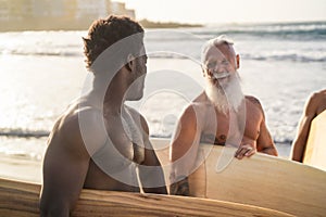 Multi generational surfer men having fun on the beach - Focus on african man