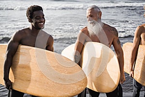 Multi generational surfer men having fun on the beach - Main focus on senior face