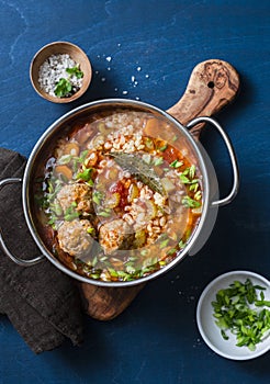 Multi grain, meatballs and vegetables soup in a pot on a blue background, top view. Comfort home cooking healthy seasonal food