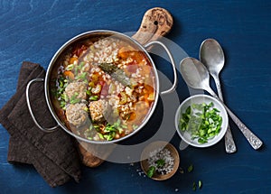 Multi grain, meatballs and vegetables soup in a pot on a blue background, top view. Comfort home cooking healthy seasonal food