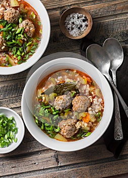 Multi grain, meatballs and vegetables soup on a wooden rustic background, top view. Comfort home cooking healthy seasonal food