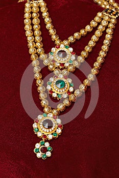 Multi layered artificial golden rani haar jewelry on a red background